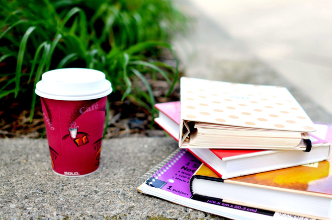 kaffekopp och böcker, anteckningsblock på en yta framför växter